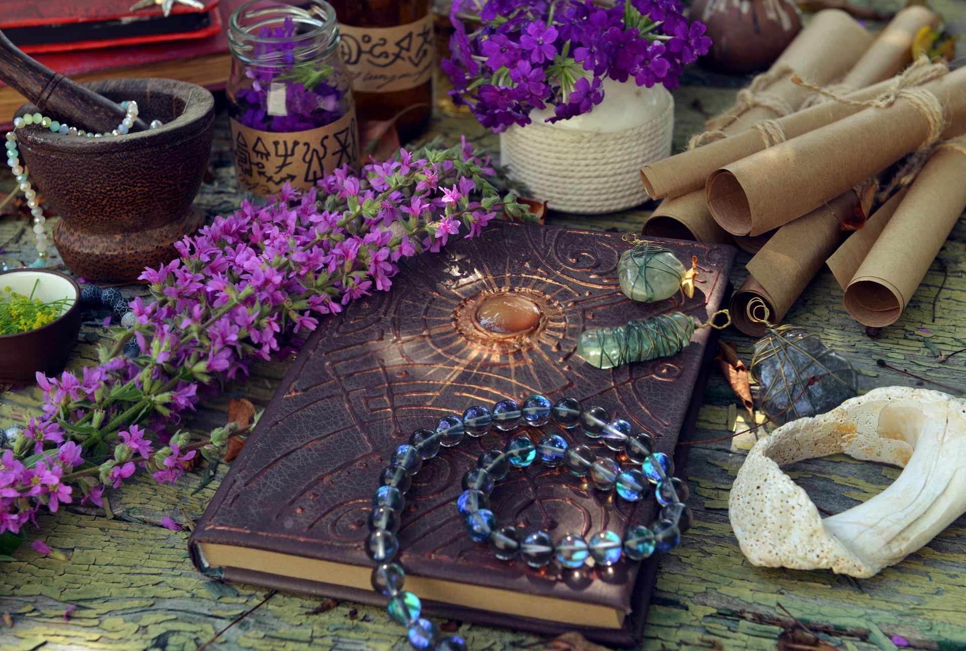 Mystic still life with magic book of spells, old paper scrolls and witchy ritual objects on old table. Occult, esoteric, wicca and divination concept. No foreign language, all symbols are fictional